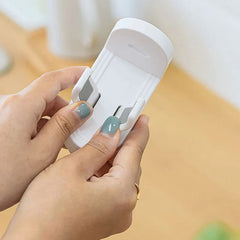 Soporte para cepillo de dientes eléctrico - Manos ajustando los dos clips de un soporte blanco montado en pared