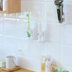 Soporte para cepillo de dientes eléctrico - Tres soportes de clip blancos montados en una pared de azulejos del baño, sosteniendo dos cepillos de dientes eléctricos y una afeitadora eléctrica