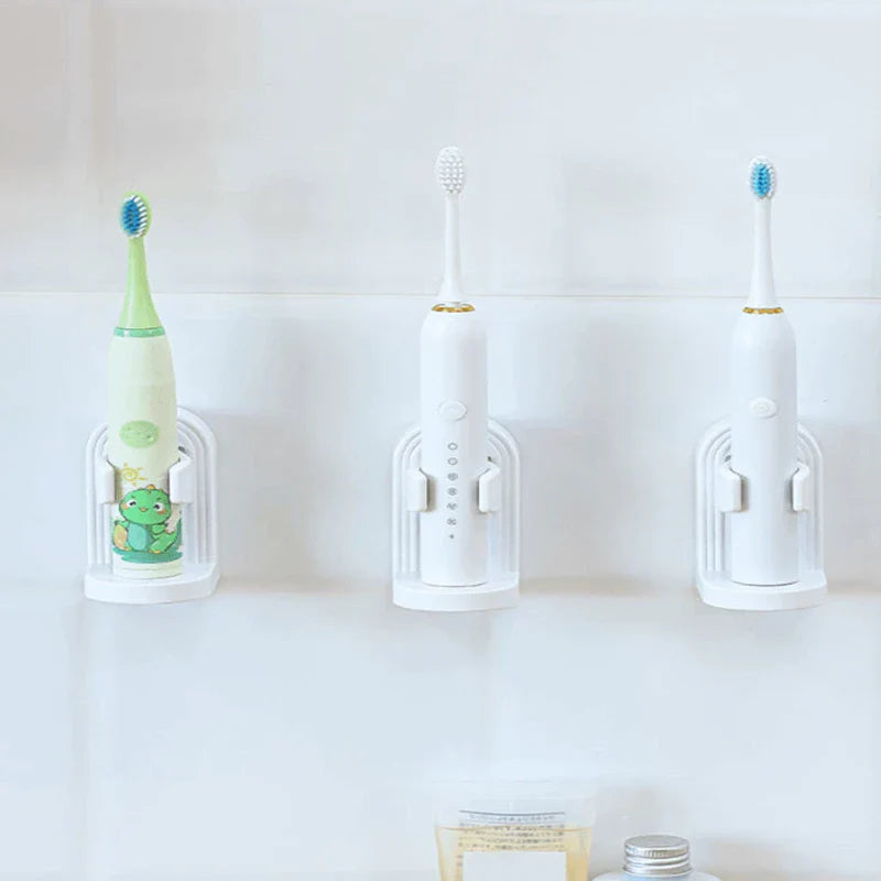 Soporte para cepillo de dientes eléctrico - Tres cepillos de dientes eléctricos reposan en tres soportes blancos iguales montados en pared sobre una pared de azulejos claros