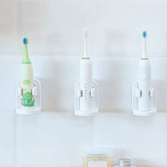 Soporte para cepillo de dientes eléctrico - Tres cepillos de dientes eléctricos reposan en tres soportes blancos iguales montados en pared sobre una pared de azulejos claros