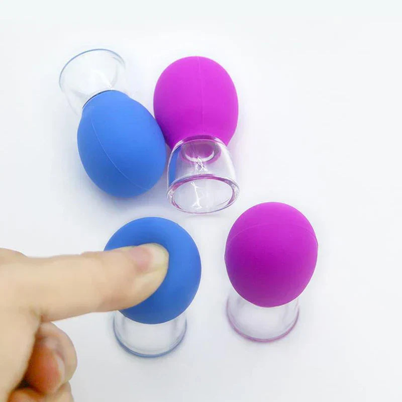 schröpfmassagegerät - Vier kleine Schröpfmassagegeräte in Blau und Violett, ein Finger drückt auf ein blaues Gerät.
