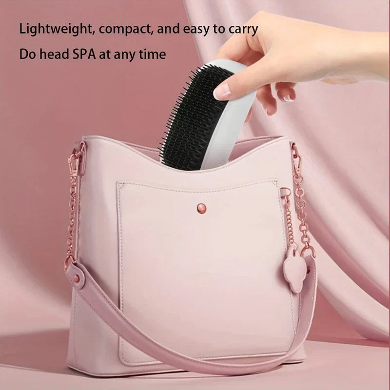 A hand places a white and black electric hair brush into a light pink handbag