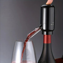 Wine Aerator Pourer - Unit attached to an open wine bottle, dispensing red wine into a waiting stemmed glass with one finger pressing the top control button