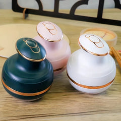 Energy Pen - Three beauty devices in dark green, pink, and white with rose-gold accents placed on a wood-grain surface.