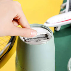 Suction Tumbler Mug - A finger lifts the battery compartment cover on a light green cylindrical device, revealing two installed AA rechargeable batteries.