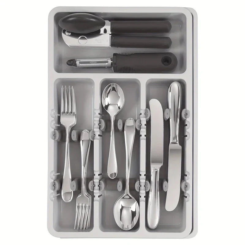 A cutlery drawer organizer holding silverware and small kitchen tools in its divided storage sections