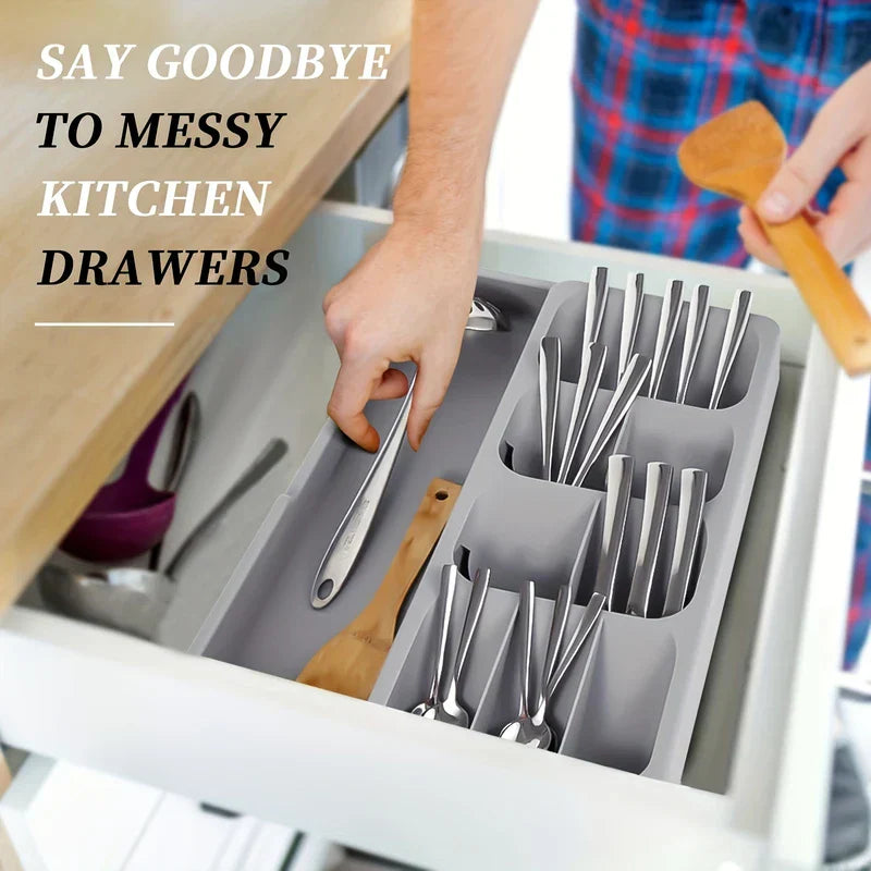 Cutlery Drawer Organizer - Adjustable storage tray placed inside an open kitchen drawer holding silverware and wooden utensils, with a person placing a utensil into the tray