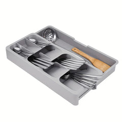 Cutlery Drawer Organizer - Expanded light gray storage tray holding arranged silverware, a slotted serving spoon, and a wooden spatula, shown against a plain white background