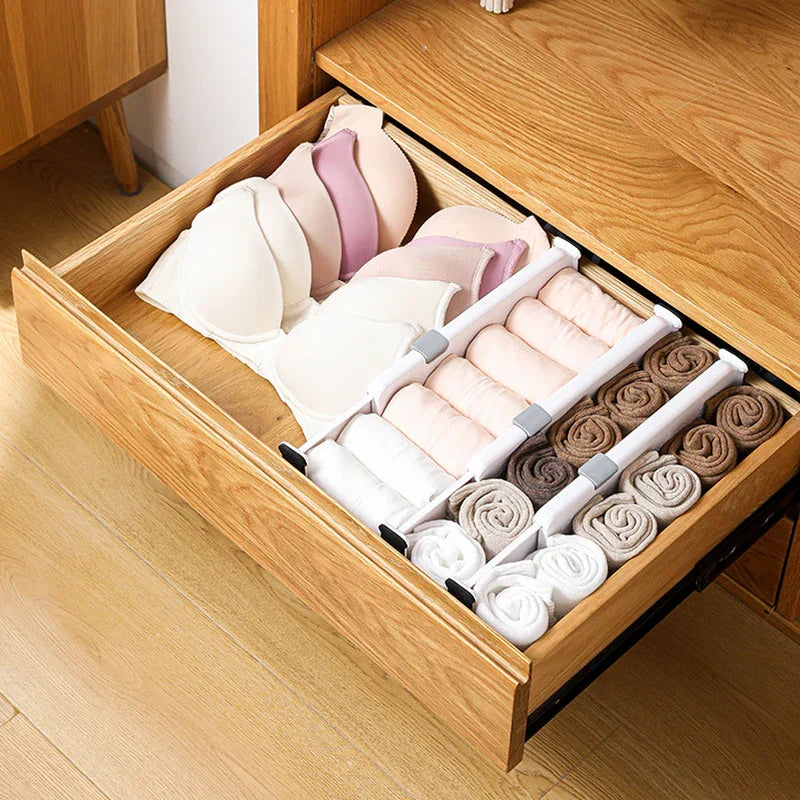 Wooden drawer holding rolled socks and bras, divided by white closet drawer organizer dividers