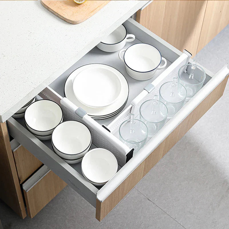 Kitchen drawer holding dishes and glass cups, sectioned with white closet drawer organizer dividers