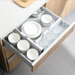 Kitchen drawer holding dishes and glass cups, sectioned with white closet drawer organizer dividers