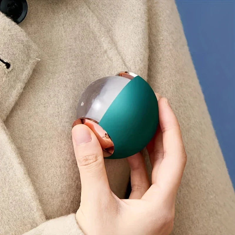 Sticky Lint Roller - Hand holds a two-tone green and clear rounded object with rose gold accents against a wool coat