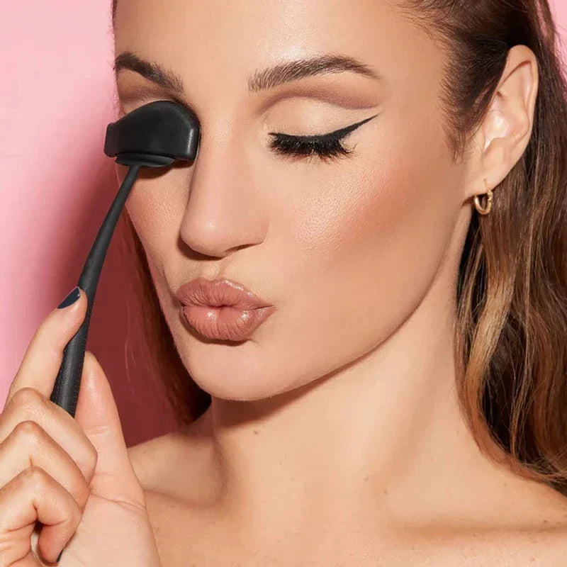Eyeshadow Stamp Crease Applicator Tool - Woman holding a black eye makeup tool against her closed right eye, left eye with winged eyeliner
