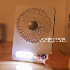 Tischventilator - Eine Hand drückt einen Knopf am weißen Tischventilator, das integrierte LED-Licht ist eingeschaltet, mit Hinweis, dass langes Drücken die Lichthelligkeit anpasst