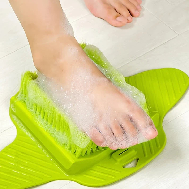 A foot covered in soap suds resting on a foot scrubber brush with pumice stone exfoliator in a bathroom.