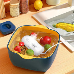 Fruit Vegetable Washing Machine - Capsule purifier operating in a produce wash basin filled with water, strawberries, limes, and an apple, placed on a wood kitchen counter next to a sink