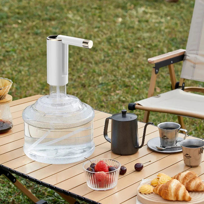 Gallon Jug - Electric water tap installed on a clear water jug placed on an outdoor camping table with drinks and snacks