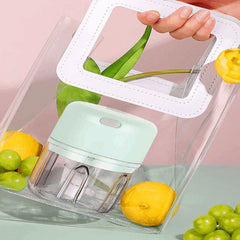 Light green mini electric food chopper inside a clear tote bag, surrounded by lemons and grapes