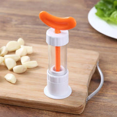 Garlic Press - Garlic prep tool placed on a wooden cutting board next to peeled garlic cloves