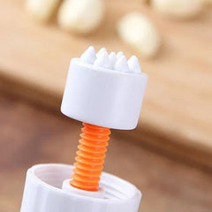 Garlic Press - Close-up of a white plastic component with raised conical spikes attached to an orange threaded screw, part of a small kitchen gadget.