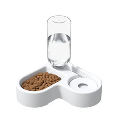 comedero de agua por gravedad - Comedero para mascotas de dos compartimentos en blanco con croquetas secas en una sección y un depósito de agua transparente acoplado