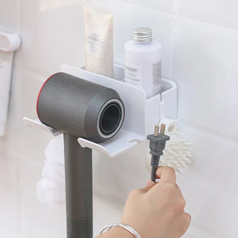 Hair Dryer Organizer - White storage unit holding a gray hair dryer and toiletries, with a hand holding the hair dryer power plug