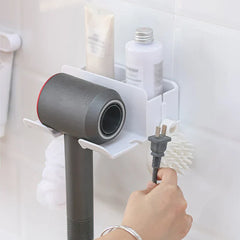 Hair Dryer Organizer - White storage unit holding a gray hair dryer and toiletries, with a hand holding the hair dryer power plug