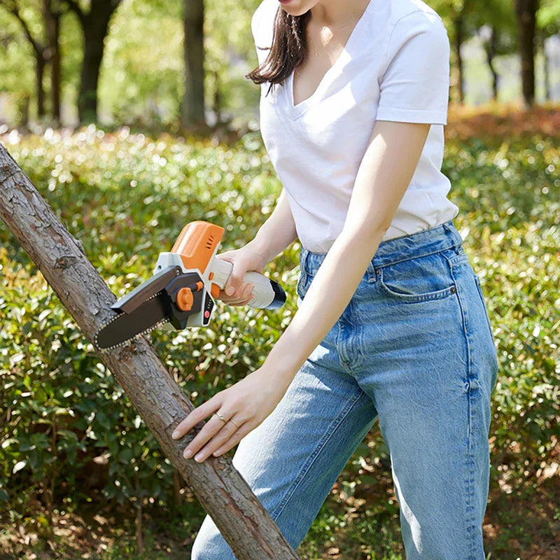 Person holding a mini chainsaw to cut a small tree branch outdoors
