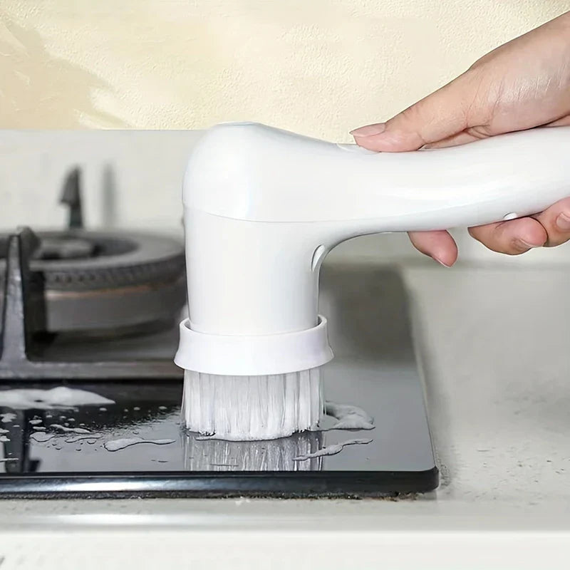 Electric Spin Scrubber - Hand holding a white electric cleaning brush, scrubbing a wet foamy kitchen stovetop surface