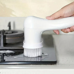 Electric Spin Scrubber - Hand holding a white electric cleaning brush, scrubbing a wet foamy kitchen stovetop surface