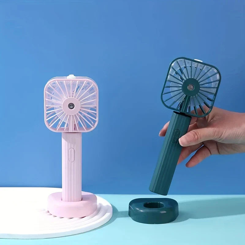 Mist Sprayer - Pink mist fan on its base; hand holds dark green mist fan lifted off its separate matching base.