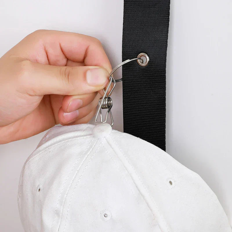 Hat Organizer - Close up of a hand attaching a white cap clip to a black strap