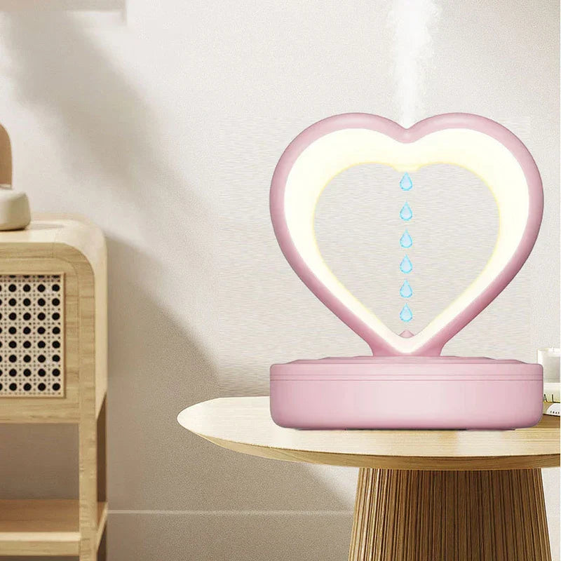 Humidifier - Pink unit placed on a light wood side table emitting cool mist, showing upward-flowing anti-gravity water drops