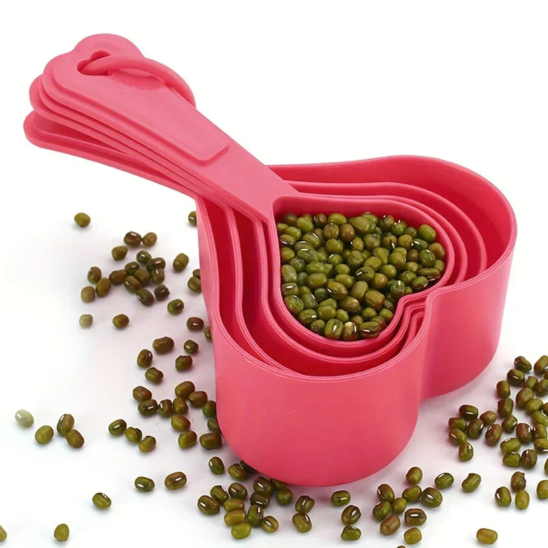 Measuring Spoons - Nested bright pink heart-shaped 4-piece kitchen measure set filled with mung beans, with loose beans scattered around the base