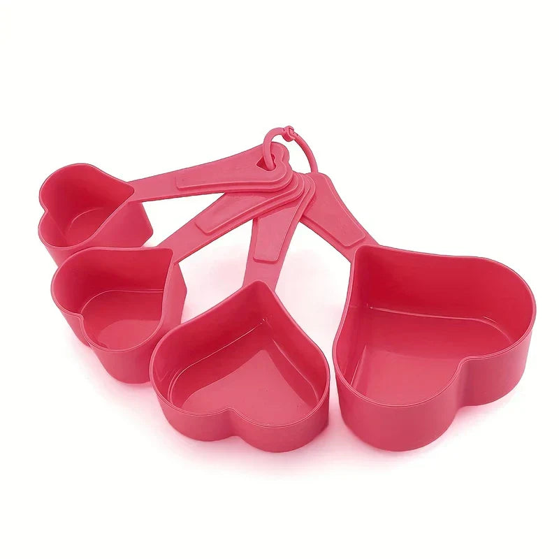 Measuring Spoons - Four pink heart-shaped plastic measuring cups fanned out, connected by a small pink ring.