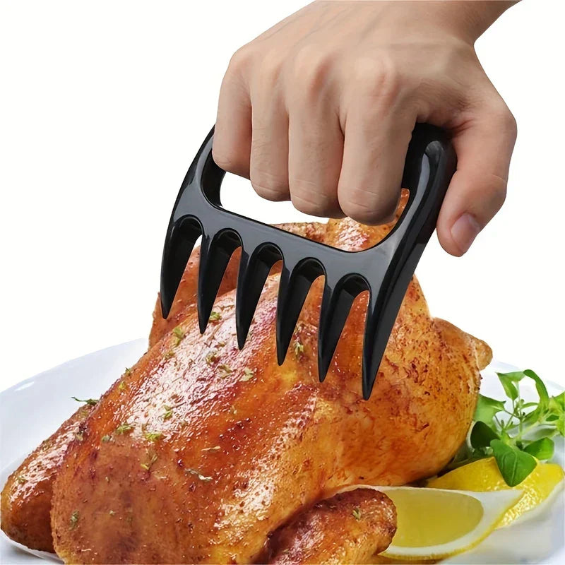 Pulled Pork Shredder Claws - Hand using a black meat shredding tool to lift a roasted whole chicken garnished with herbs and lemon on a white plate