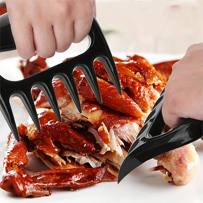 Pulled Pork Shredder Claws - Two hands hold black bear claw meat separators to shred and pull apart cooked roasted poultry on a plate
