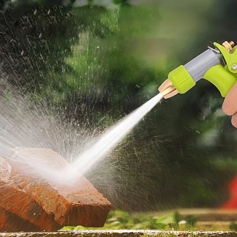 düse für gartenschlauch - Hand hält eine grün-graue Sprühdüse und sprüht Wasser auf einen roten Ziegelstein