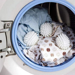 Reusable Dryer Balls - Three spiked hedgehog laundry tools placed inside a clothes dryer drum resting on folded linens