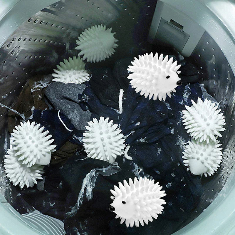 Reusable Dryer Balls - Multiple white hedgehog-shaped spiky objects tumbling among dark laundry inside a washing machine drum