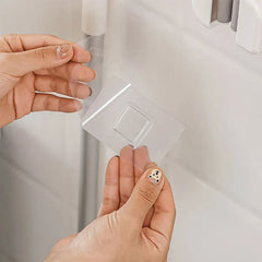 Mop Broom Holder - Two hands holding a clear adhesive mounting tab for the mop holder