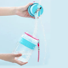 Two hands hold a blue blender lid and a clear bottle under running water; the smoothie maker tumbler bottle is shown in two separate pieces.