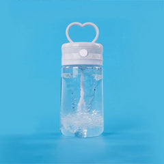 Insulated Coffee Travel Mug - Clear plastic water bottle with white heart handle lid, mixing liquid inside, set against solid bright blue background