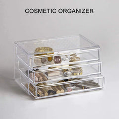 Cosmetic Organizer Case - Clear 3-drawer cosmetic organizer holding jewelry and makeup, text "COSMETIC ORGANIZER" above it, on light gray surface