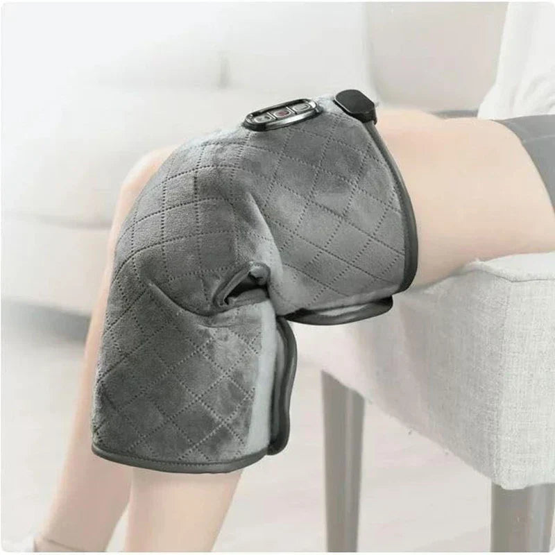 Knee Compression Sleeve - Gray quilted heated knee massager worn on a person's bent knee, secured with a strap