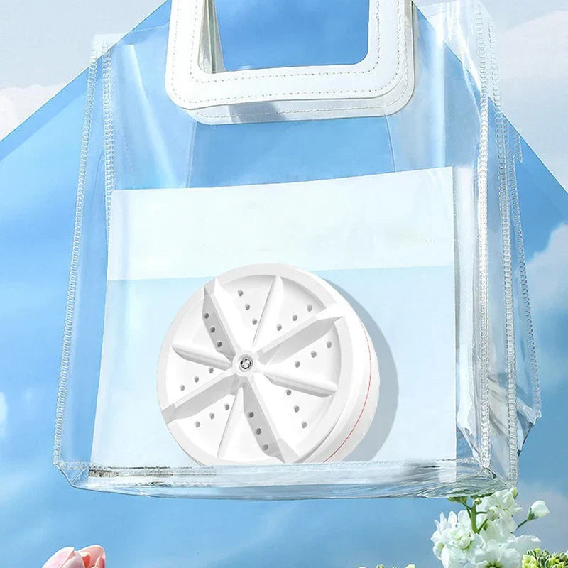 Mini Washer - White compact ultrasonic portable mini washing machine turbine, inside a clear transparent PVC tote bag against a light blue sky background.