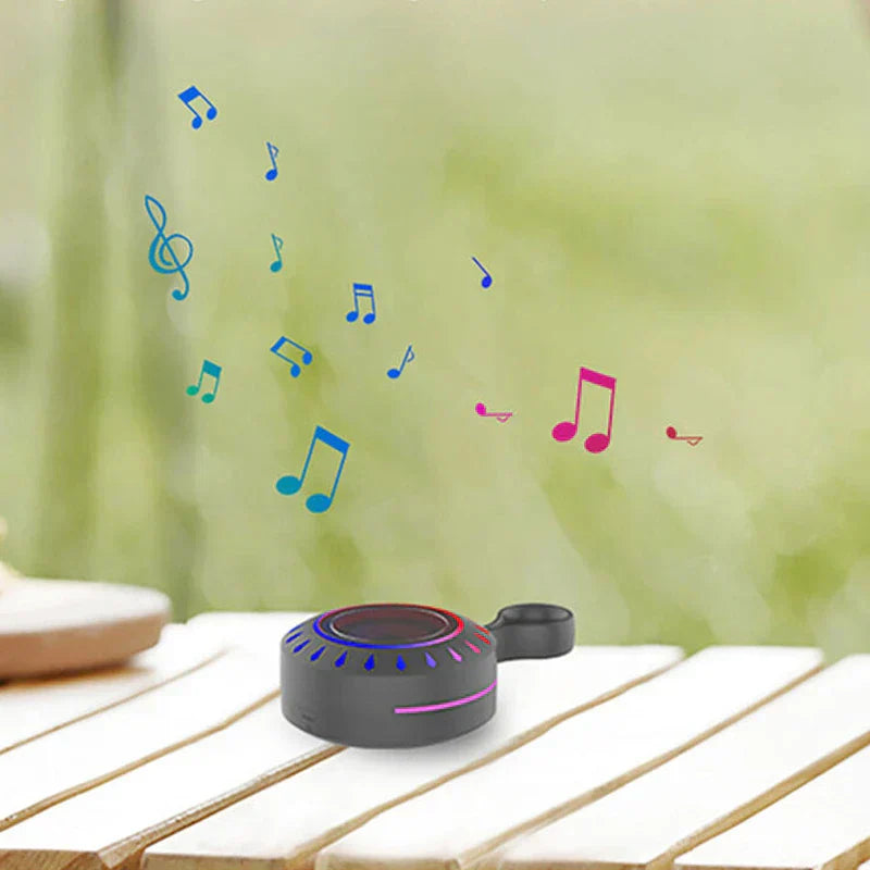 Portable Bluetooth Speaker - Black speaker resting on a slatted outdoor wooden table, with illustrated music notes indicating audio playback