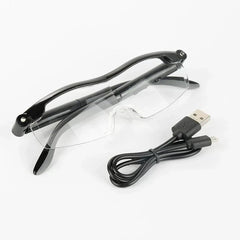 نظارات قراءة - نظارة مكبرة موضوعة بجانب كابل شحن USB أسود ملفوف على سطح أبيض مستوٍ