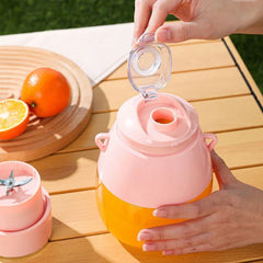 Blender Bottle - Hands opening the flip-top drinking spout on the pink juicer with orange juice inside, blade unit placed beside it on a wooden table
