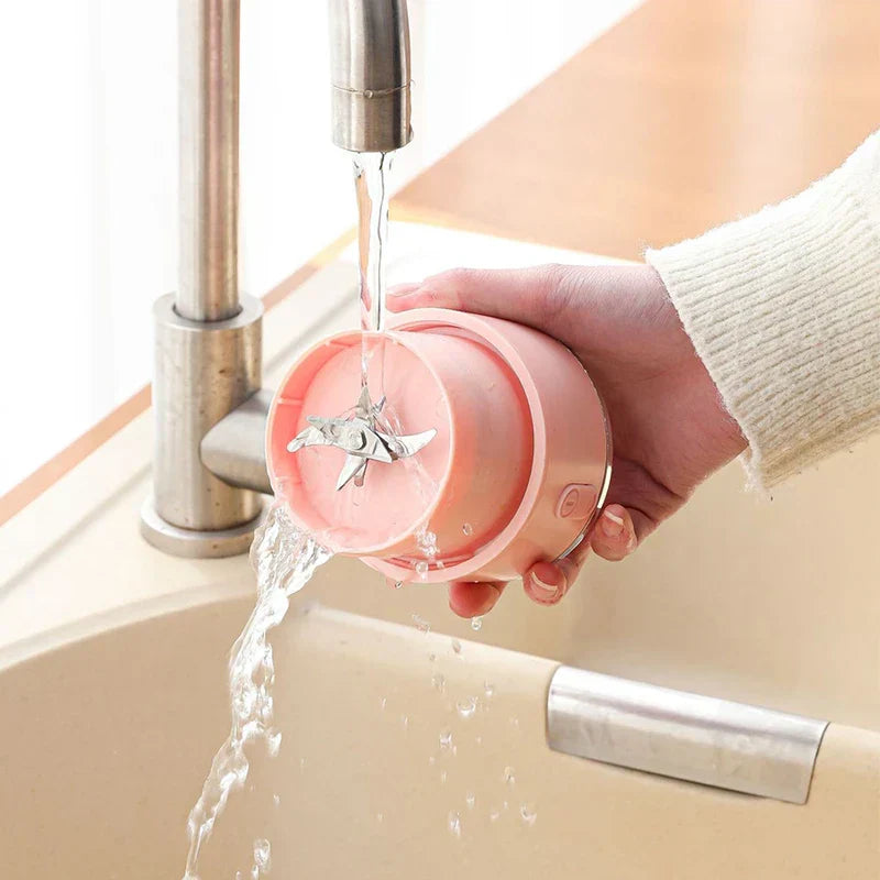 Blender Bottle - Hand rinsing the detached pink juicer blade unit under running water at a sink